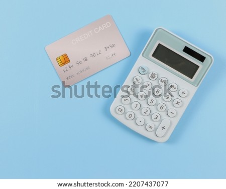 Top view or flat lay of blue calculator and credit card on blue background. Business and finance concept.