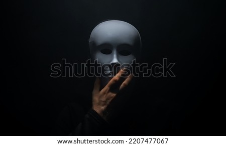 Man in a hoodie takes off his mask. Royalty-Free Stock Photo #2207477067