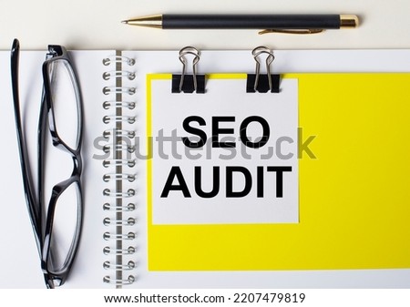 Paper with the text SEO AUDIT on a yellow background, glasses, pen, top view, school, education, knowledge, business.
