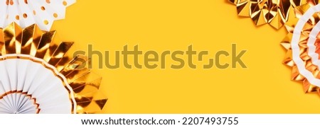 Banner with frame made of gold colored paper fans on a yellow background.