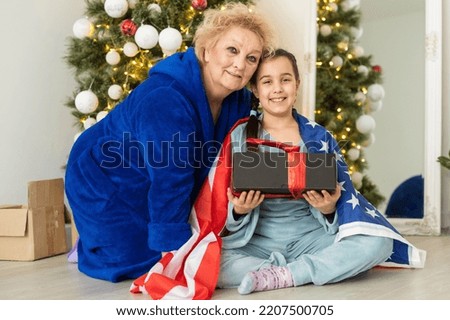Family holding flag of USA at christmas. grandmother and granddaughter