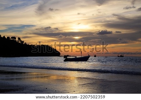 Wooden fishing boat on the seaBeautiful twilight sky and fishing boat on the seaThe sun with dramatic clouds on the skyTropical beach Andaman sea in Thailand