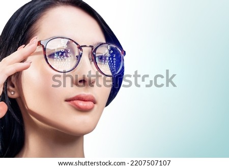 Woman with eye chart reflected in glasses. Ophthalmologist consultation. Optometry concept. Royalty-Free Stock Photo #2207507107