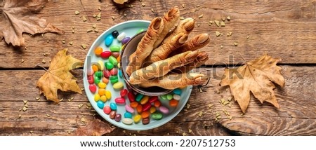 Halloween cookies, autumn leaves and candies on wooden background