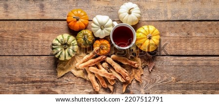 Halloween cookies, autumn leaves, pumpkins and tea on wooden background, top view
