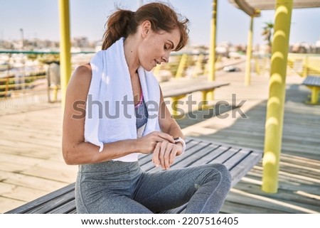 Young caucasian woman wearing sportswear looking watch at street Royalty-Free Stock Photo #2207516405