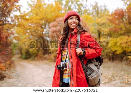 Young woman- tourist taking pictures in the autumn forest.  Rest, relaxation, tourism, nature, lifestyle concept.