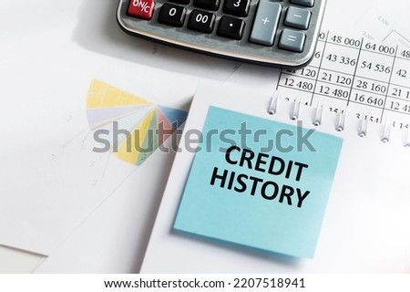 CREDIT HISTORY on a blue card in front of an office desk. Business concept