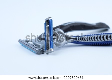 Black shaving razor and blue shaving razor isolated on white background, standing sideways Royalty-Free Stock Photo #2207520631