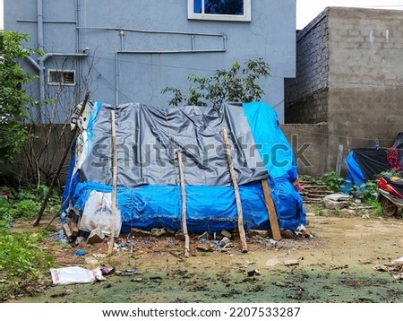 Stock photo of blue color plastic handmade temporary housing structure or shelter or tent for homeless people or construction worker near construction site at Hyderabad, Telangana, India.