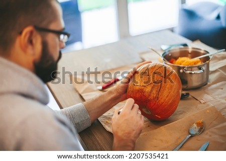 Man drawing a face for Halloween pumpkin