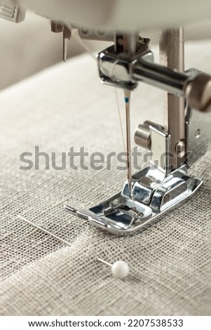 Modern sewing machine presser foot with linen fabric and thread, closeup, copy space. Sewing process clothes, curtains, upholstery. Business, hobby, handmade, zero waste, recycling, repair concept