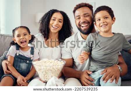 Love, laugh and watching tv or a movie with a happy family eating popcorn, having fun and smile together in home. Portrait of latino parents and children, enjoy the weekend and feeling carefree Royalty-Free Stock Photo #2207539235