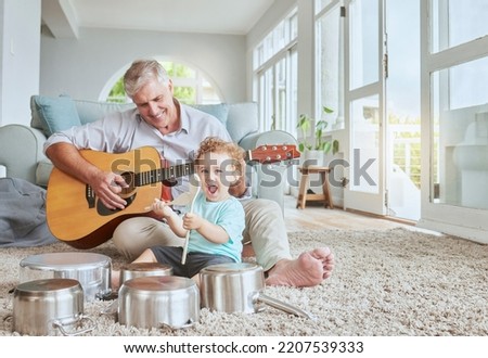 Child drummer with grandfather, guitar and music playing with pot drums in the living room at house. Happy, excited and smile of boy bonding and spending time with his elderly grandpa in family home. Royalty-Free Stock Photo #2207539333