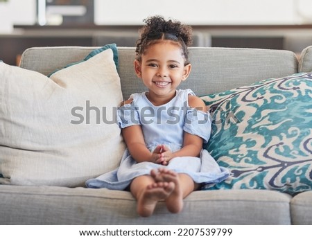 Children, girl and happy with a cute female kid on a sofa in the living room of her home alone. Kids, cute and smile with a portrait of an adorable little female child in a colombia house in the day Royalty-Free Stock Photo #2207539799