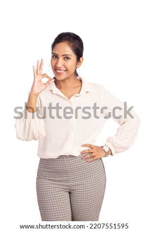 Cheerful Indian young business woman showing okay hand sign isolated on white.