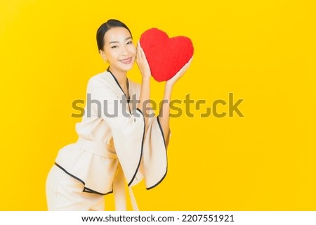 Portrait beautiful young business asian woman with heart pillow shape on yellow color background