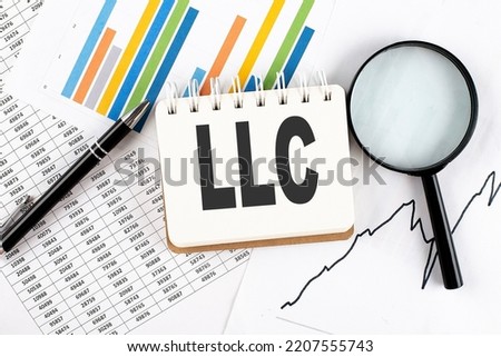 LLC Limited Liability Company text on a notebook on the graph background with pen and magnifier