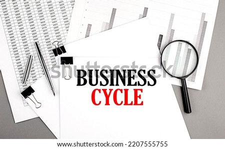 BUSINESS CYCLE text on a paper on chart background