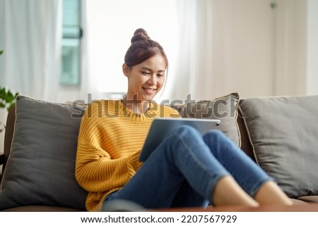 Portrait of a young Asian woman using a tablet on the sofa.