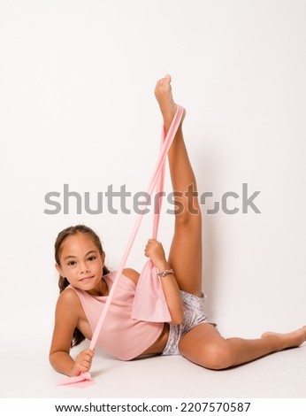 Full length photo of young attractive little girl sit floor stretching training gym isolated over white color background