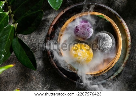 Japanese dessert made from tender rice dough with vanilla ice cream, Mochi. Three different Mochi flavored with mango, blueberry and green tea. The mochi are in a wicker basket with bamboo leaves at t