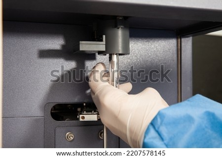 Scientist loading a test tube containing a patient sample on the  flow cytometer for analysis. Flow cytometer Royalty-Free Stock Photo #2207578145