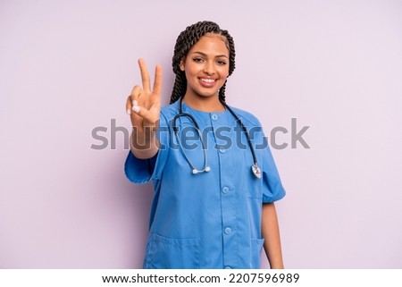black afro hairstyle woman smiling and looking friendly, showing number two. nurse concept