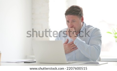 Man Coughing while using Laptop in Office