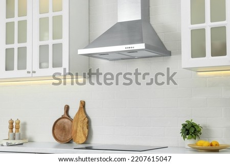 Elegant kitchen interior with modern range hood over cooktop and stylish furniture Royalty-Free Stock Photo #2207615047