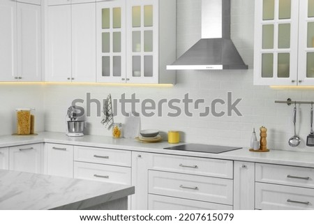 Elegant kitchen interior with modern range hood over cooktop and stylish furniture
