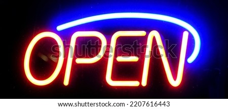 Open sign neon on glass window or door for business at night glowing with color