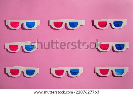 Old white paper 3d glasses with blue and red lenses on a pink background with copy space. Retro stereoscopic 3D cardboard glasses for watching 3D movies. Vintage background with stereoscope eyewear.