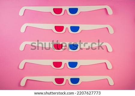 Old white paper 3d glasses with blue and red lenses on a pink background. Retro stereoscopic 3D cardboard glasses for watching 3D movies. Vintage background with stereoscope eyewear.