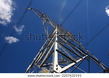 high voltage electrical tower under the blue sky, profiles and cables highlighted Royalty-Free Stock Photo #2207632193