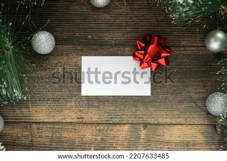 Blank white postcard on dark wooden background with fir branches and silver ball