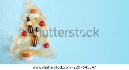 Composition from zero waste cosmetics containers,view from above.Golden ribbon lies like christmas tree and red balls around,large banner with negative space.