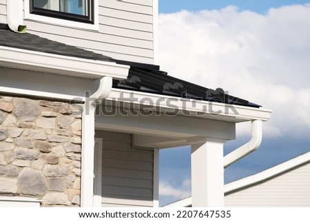New rain gutter on a white home against blue sky drain corner outside Royalty-Free Stock Photo #2207647535