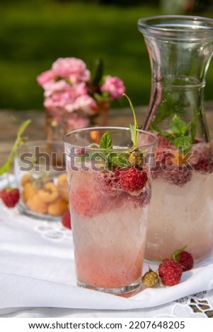 Home lemonade of raspberries, jugs and glasses with raspberry lemonade