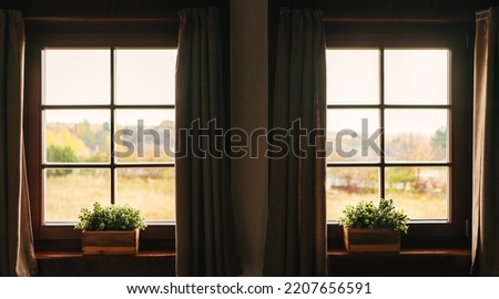 Two country house windows with a windowsill flowers pots showing a countryside landscape. Geometrical indoor concept.