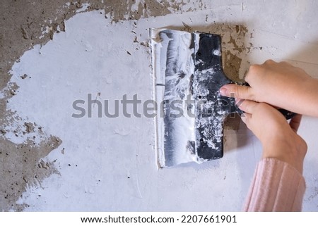 Children's hands work with a spatula. Alignment of walls, finishing works. Applying putty