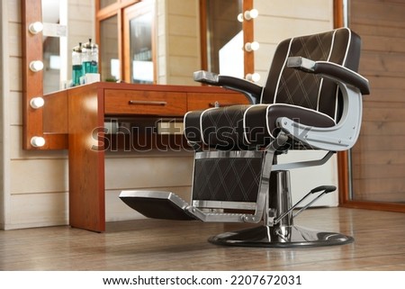 New empty chair near table with mirror in hairdressing salon Royalty-Free Stock Photo #2207672031