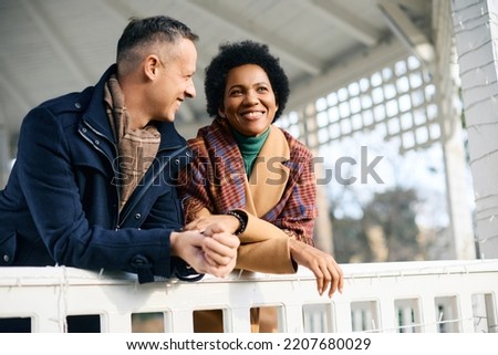 Happy multiracial couple spending winter day at the park. Focus is on African American woman.  Royalty-Free Stock Photo #2207680029