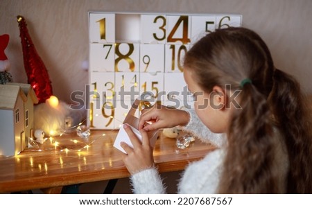 A girl opens a box of an original advent calendar with golden numbers from 1 to 24, New Year's crafts, gift boxes for every day, magical moments, a Christmas miracle in every home, gifts for Christmas