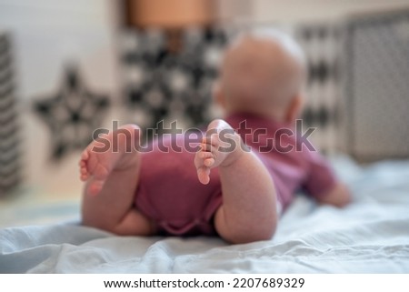 Rear view of the baby lying on his tummy and looking at black and white pictures