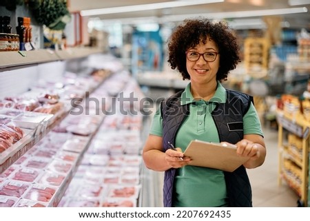 Happy quality control manager working in supermarket and looking at camera.