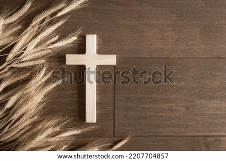 Wood cross with border of ears of wheat on a dark wood background with copy space