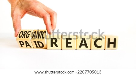 Organic or paid reach symbol. Businessman turns wooden cubes and changes words paid reach to organic reach. Beautiful white table white background, copy space. Business organic or paid reach concept.