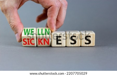 Sickness or wellness symbol. Concept words Sickness or Wellness on wooden cubes. Businessman hand. Beautiful grey table grey background. Business sickness or wellness concept. Copy space.