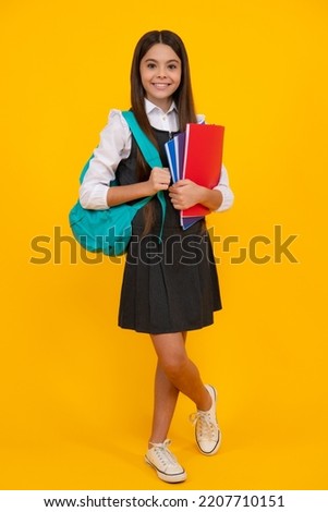 Back to school. Teenager school girl hold book and copybook ready to learn. School children with school bag on isolated yellow studio background.